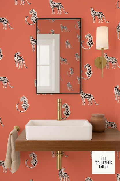 a bathroom with a white sink and a mirror, set against a vibrant orange wall with a repeating pattern of leopard-like animals.