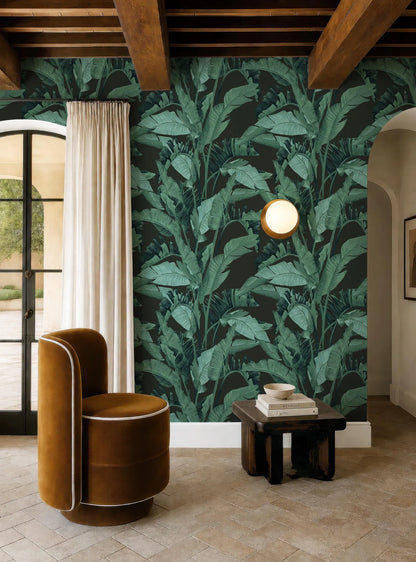 a living room with a large green wallpapered wall, a brown armchair, a wooden side table, and a round light fixture.