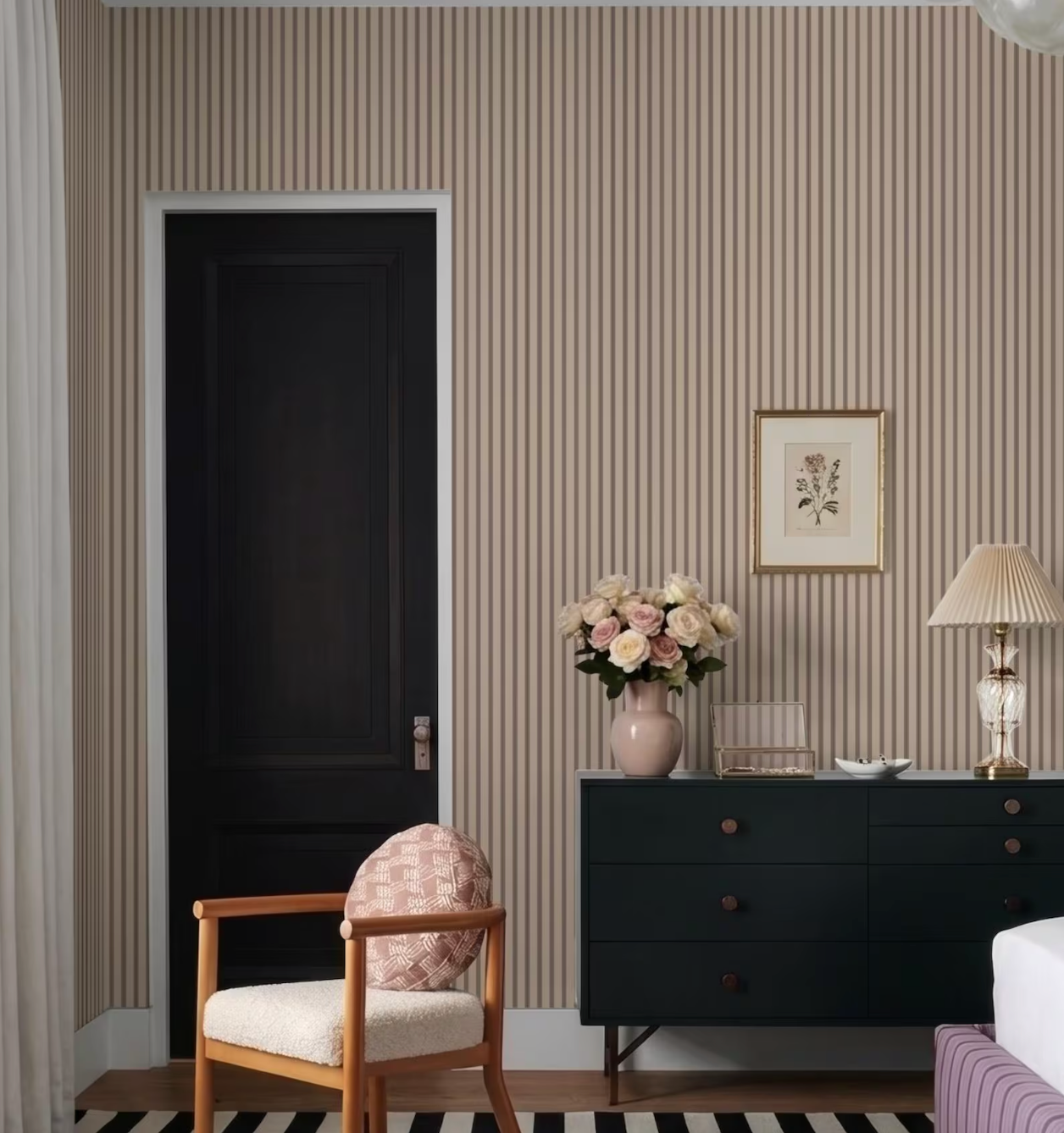 a bedroom with a black door, a wooden chair, a black dresser, and a framed picture on the wall.