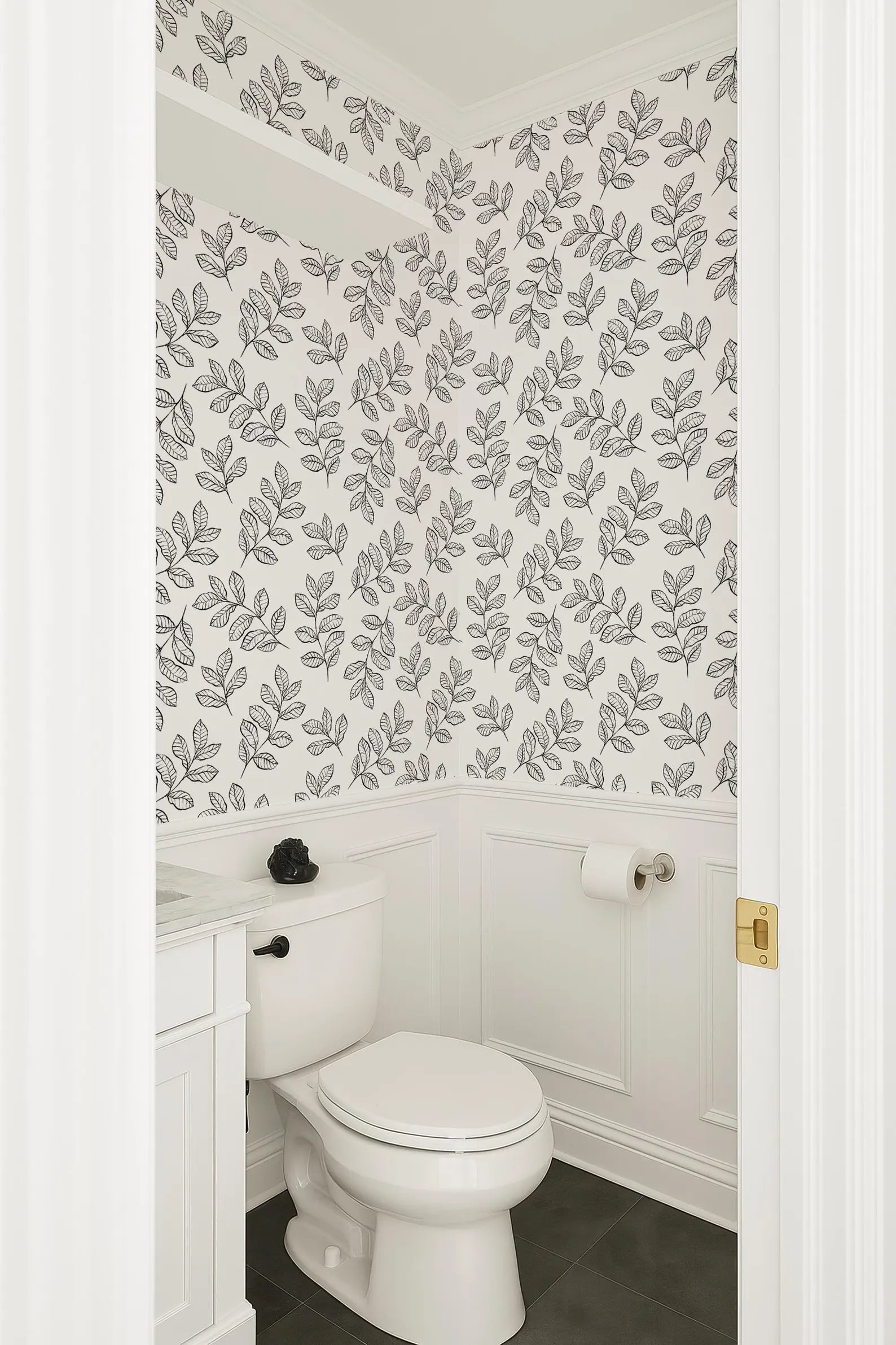 a bathroom with a white toilet and a white vanity. The walls are decorated with a black and white leaf pattern wallpaper.