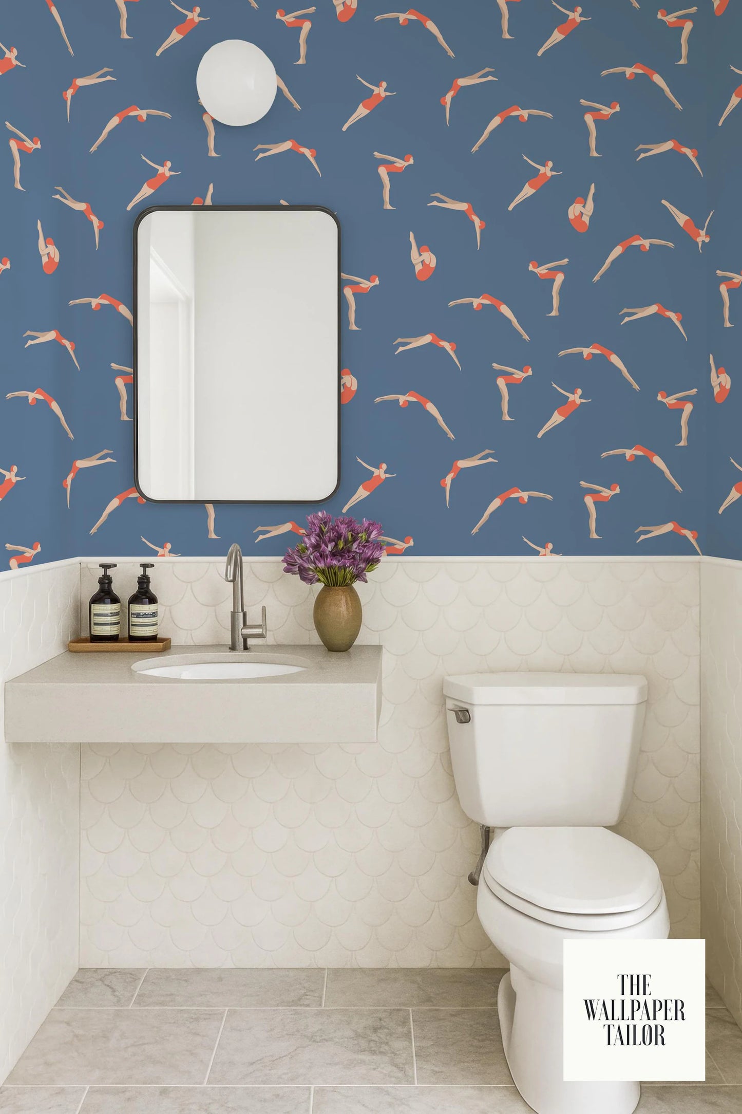 a bathroom with a blue and white color scheme, featuring a white toilet, sink, and mirror. The walls are adorned with a pattern of orange and white swimming figures, creating a vibrant and playful atmosphere.