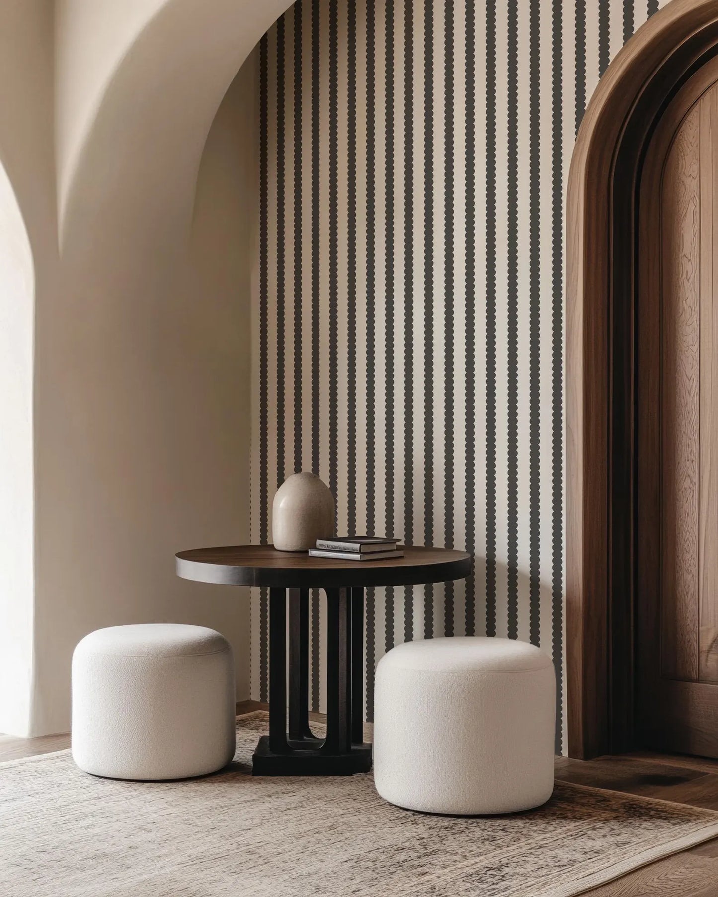 a modern and minimalist interior design with a round wooden table, two white ottomans, and a striped wall behind the table.
