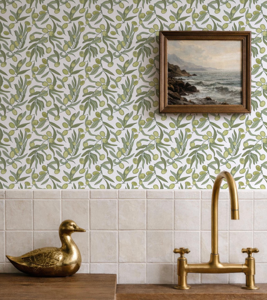 a kitchen scene with a gold duck figurine, a framed landscape painting, and a gold faucet on a tiled wall.