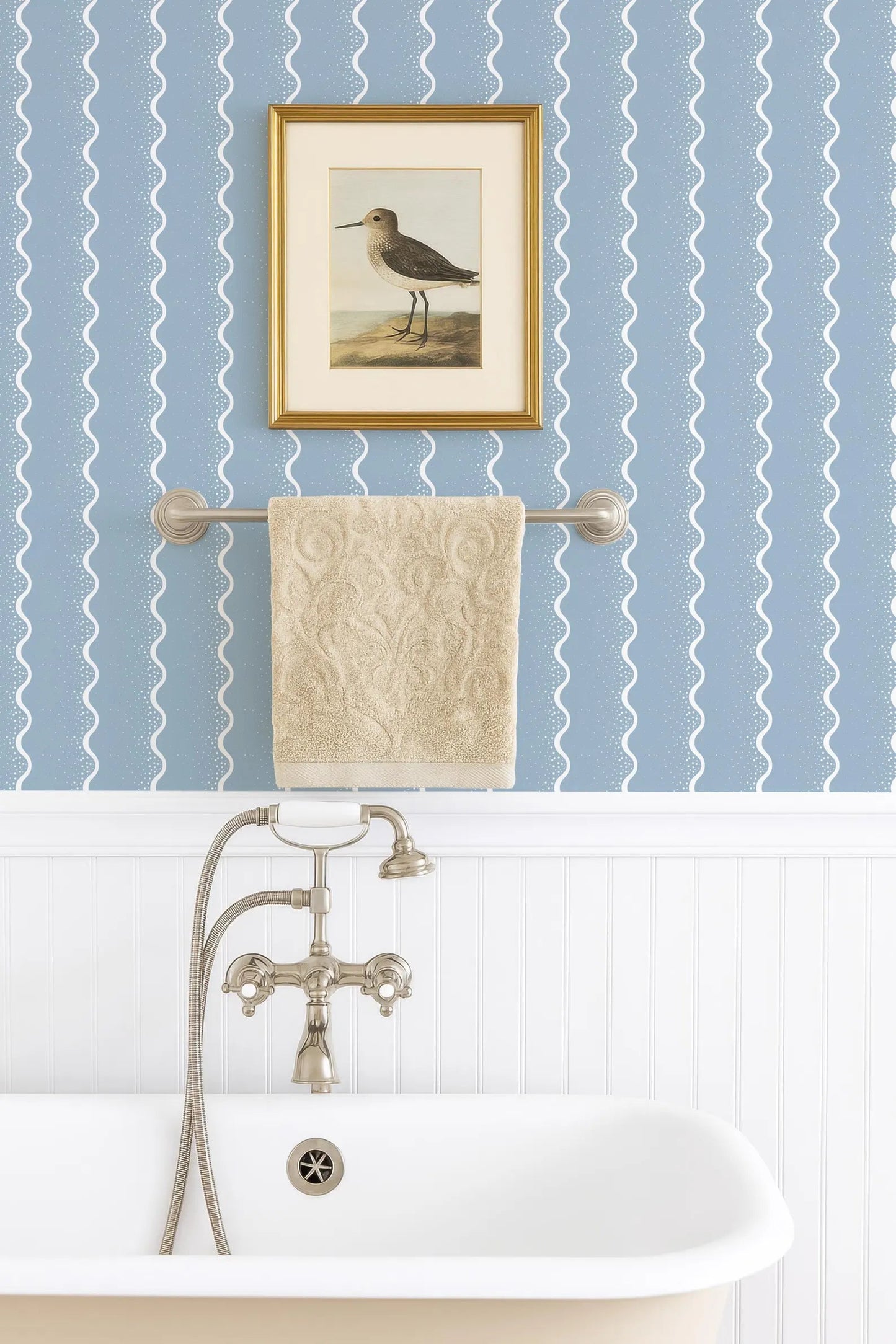 a bathroom with a clawfoot bathtub, a towel rack, and a framed painting of a bird on the wall.