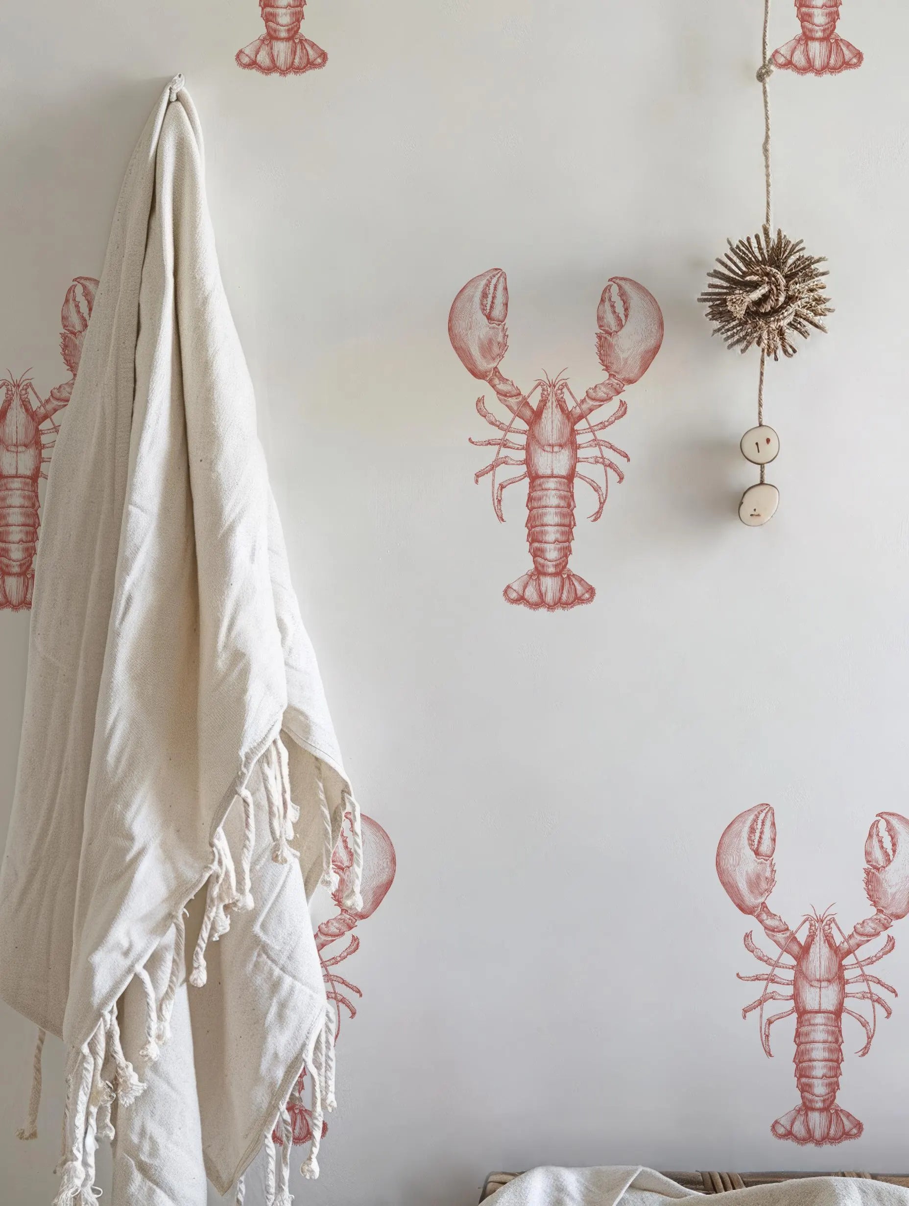 a wall with a wallpaper design of red lobsters, and there is a towel hanging on the wall next to it.