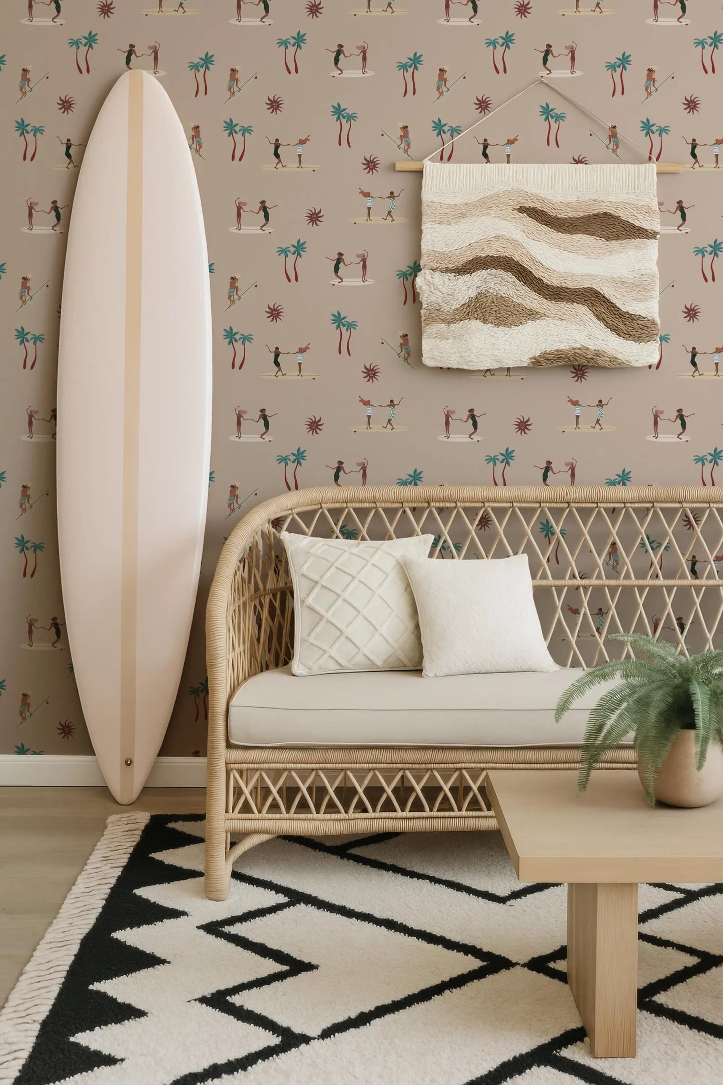 a cozy living room with a wicker bench, a white surfboard, and a woven rug. The wall behind the furniture is decorated with a patterned wallpaper, and a woven tapestry hangs on the wall. A potted plant is placed on a table in the room, adding a touch of greenery to the space.