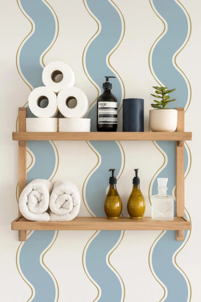a bathroom setting with a wooden shelf displaying various toiletries and towels. The shelf has three rolls of toilet paper, a black soap dispenser, a small potted plant, and two bottles of lotion. The background has a blue and white striped pattern.