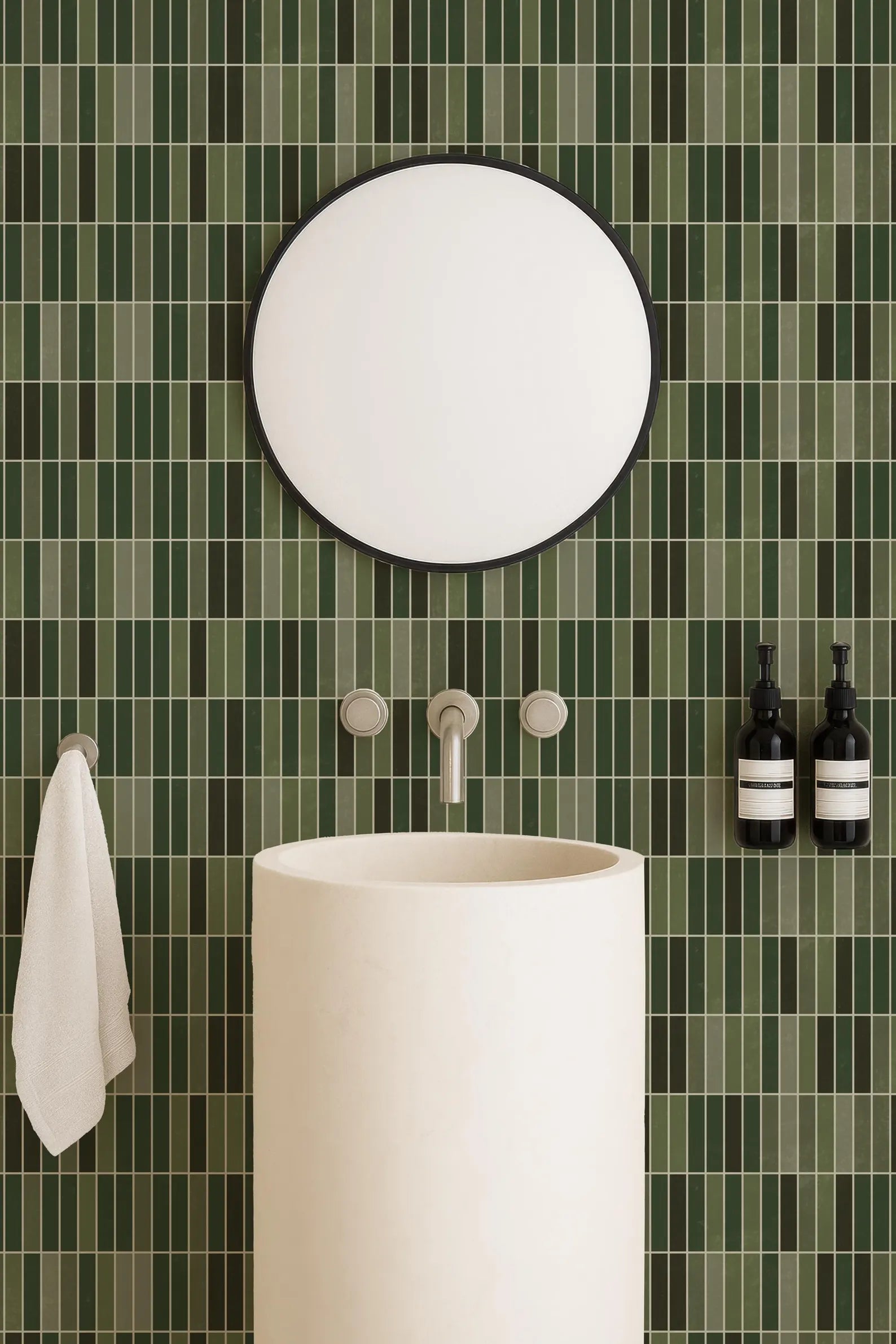 a bathroom with a white sink, a round mirror, and green tiles on the wall. There are also two bottles of soap on the wall.