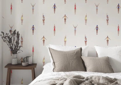 a bedroom with a bed, a nightstand, and a wallpapered wall with a repeating pattern of swimming figures.