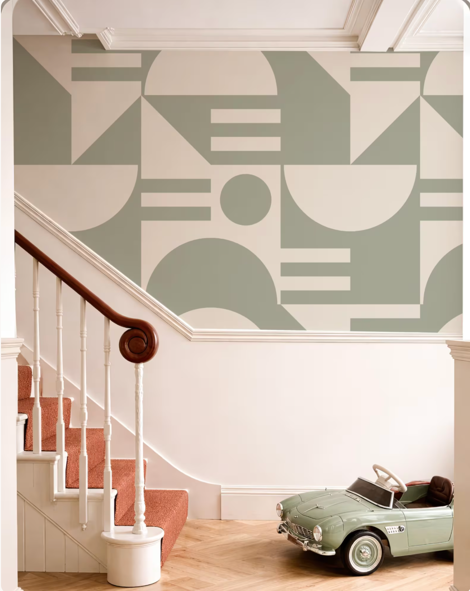 a staircase with a wooden handrail, a small toy car, and a geometric patterned wall behind the staircase.