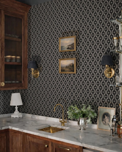 a stylish and modern bar area with a black and white patterned wallpaper, a marble countertop, and a gold faucet. The space is decorated with framed artwork, a potted plant, and various glassware, creating a sophisticated and elegant atmosphere.