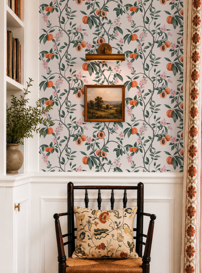a cozy corner with a wooden chair, a floral patterned wall, a framed landscape painting, and a potted plant.