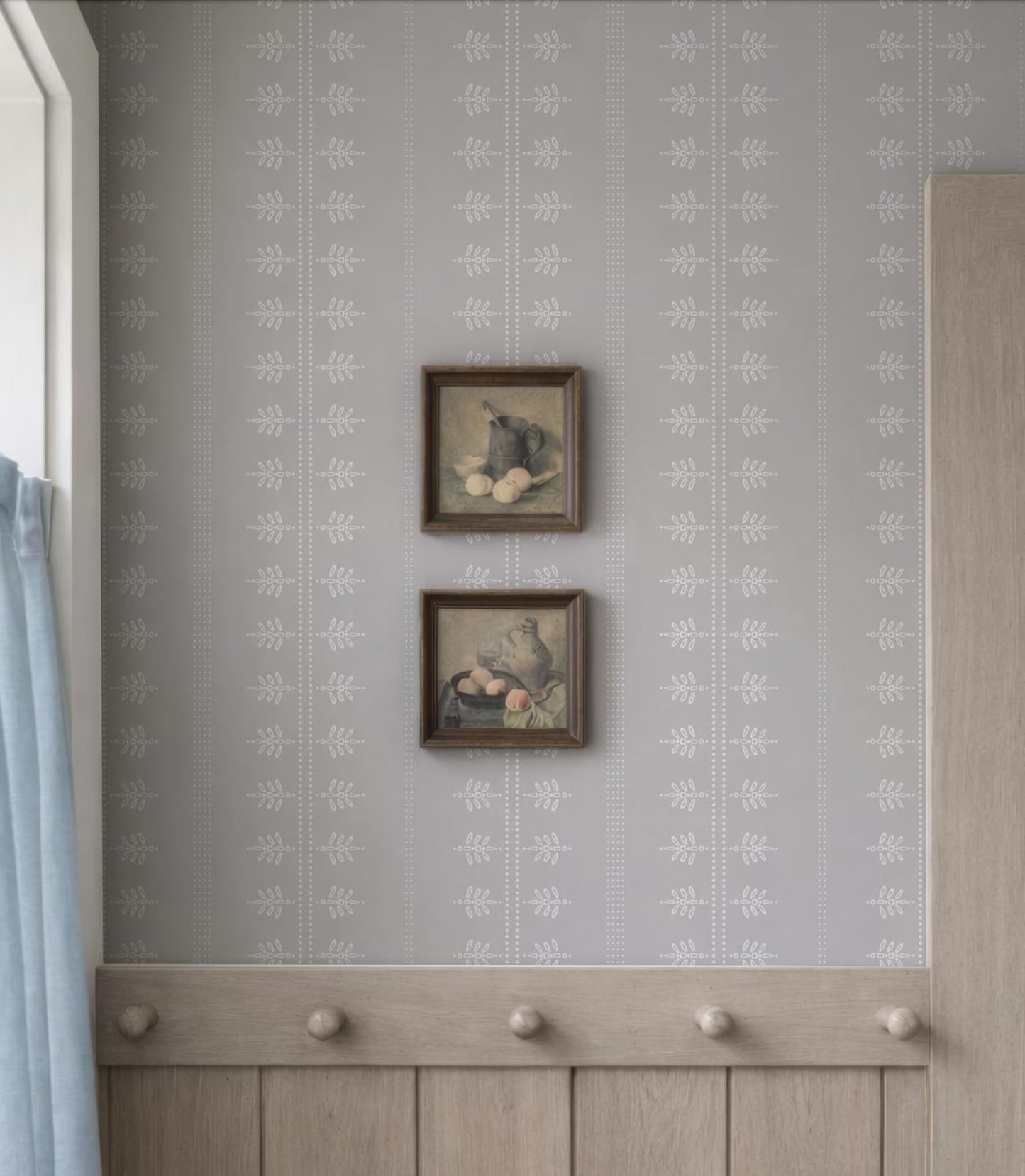 two framed artworks hanging on a wall, with a wooden coat rack below them.
