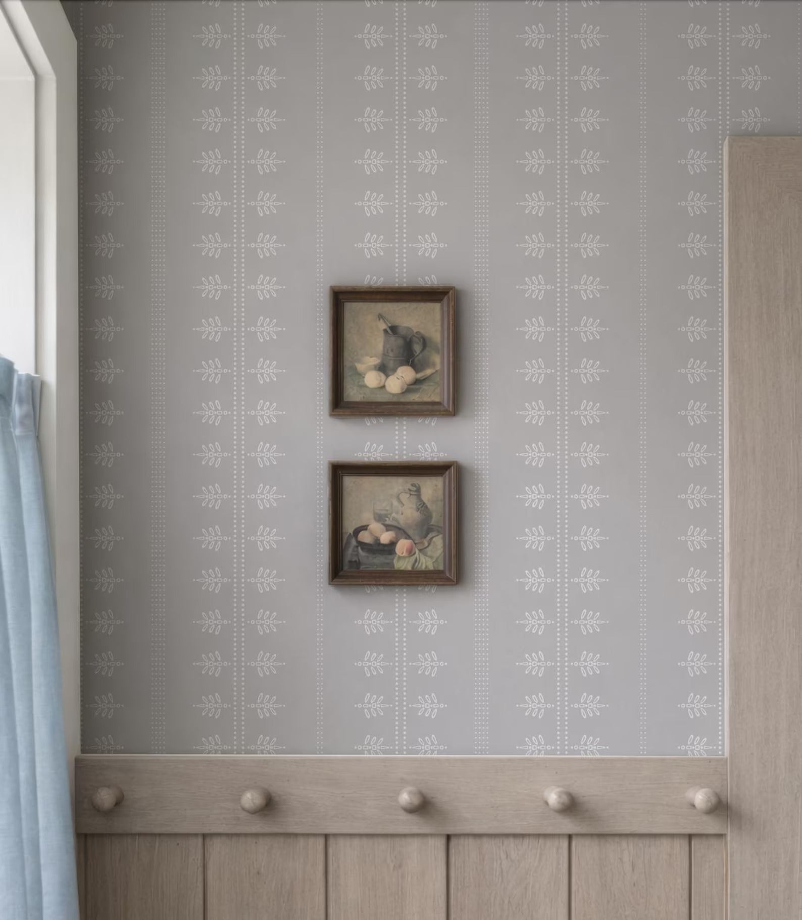 two framed artworks hanging on a wall, with a wooden coat rack below them.
