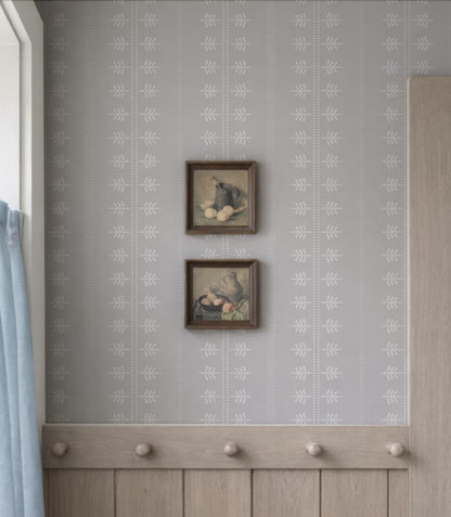 two framed artworks hanging on a wall, with a wooden coat rack below them.