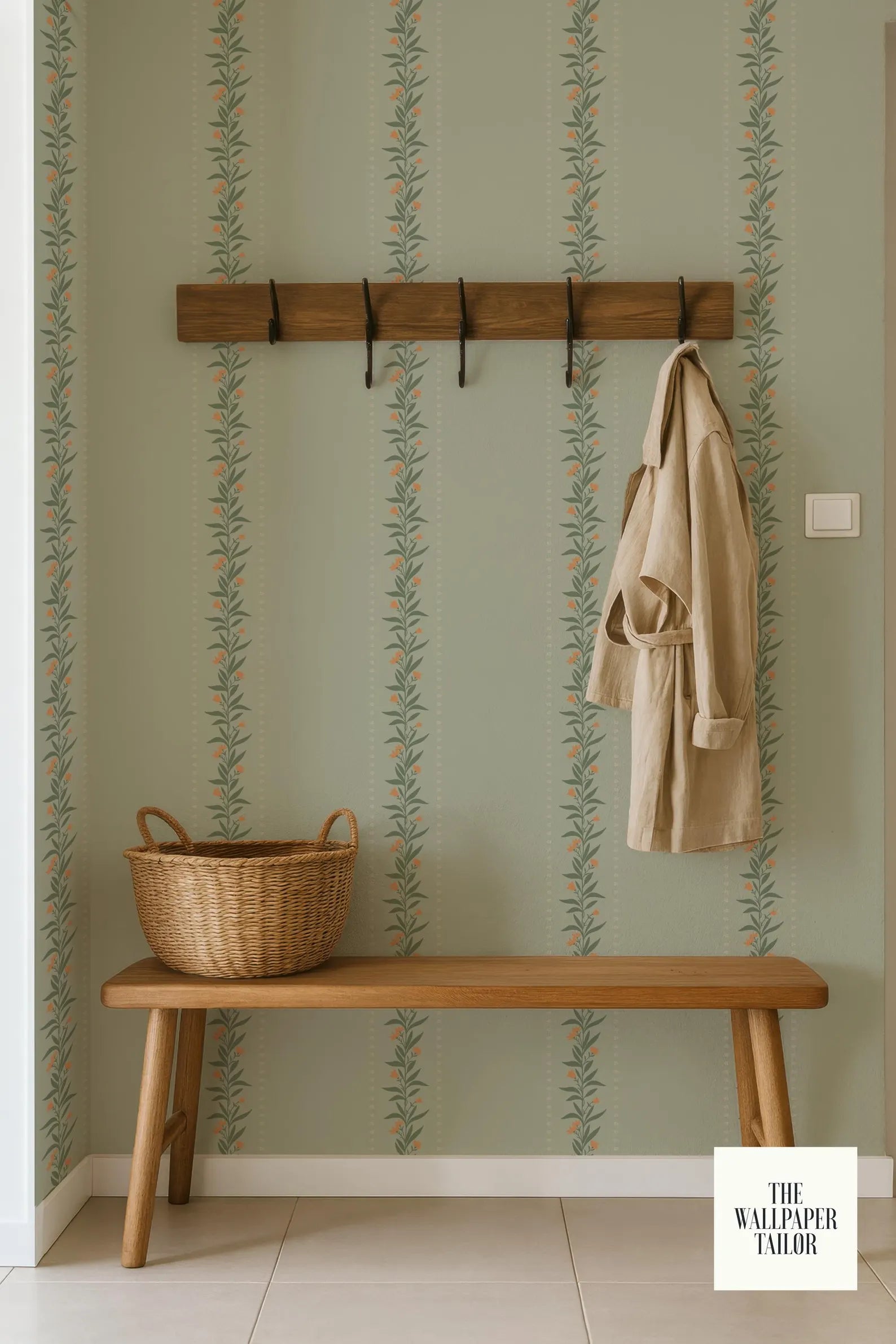 a wooden bench with a wicker basket on it, placed against a wall with a patterned wallpaper. A coat is hanging on a wooden coat rack above the bench.