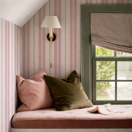 a cozy and inviting bedroom scene, featuring a window with a green frame and a white lamp, a pink and white striped wallpaper, and a comfortable bed with a green pillow and a pink pillow.