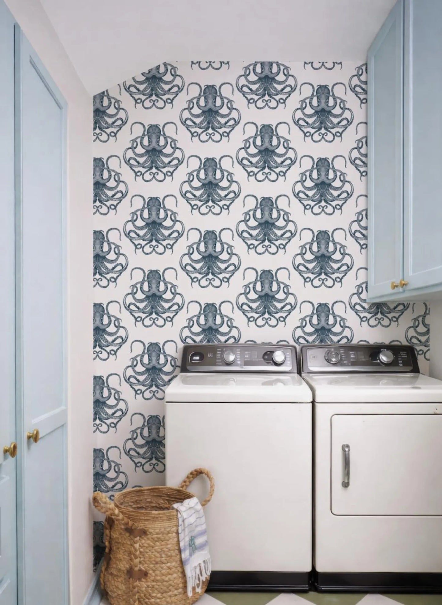a laundry room with a patterned wallpaper of octopuses on the wall, two washing machines, and a basket on the floor.