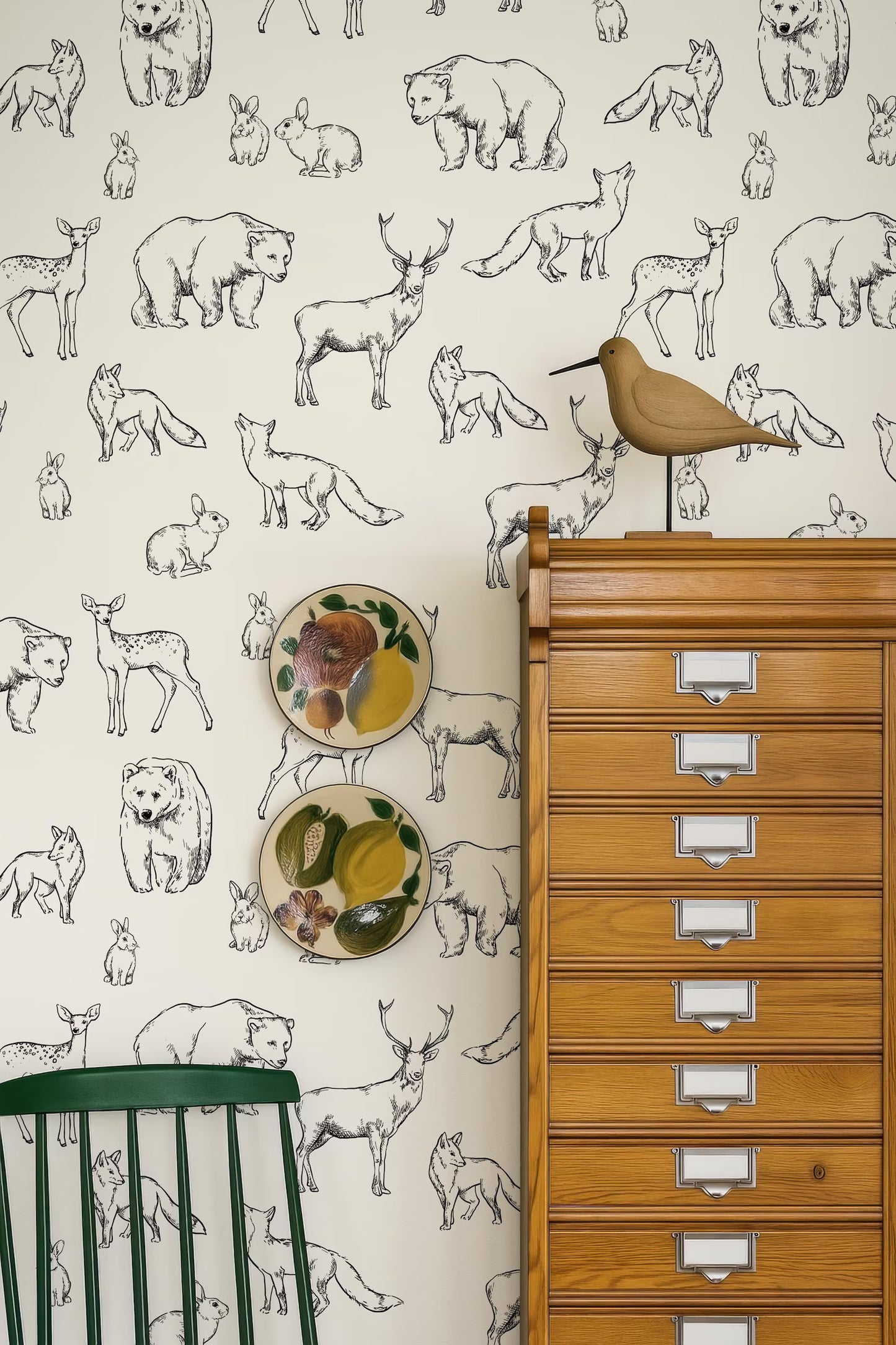 a wallpapered wall with various animal illustrations, including bears, deer, and birds, as well as a wooden cabinet with multiple drawers.