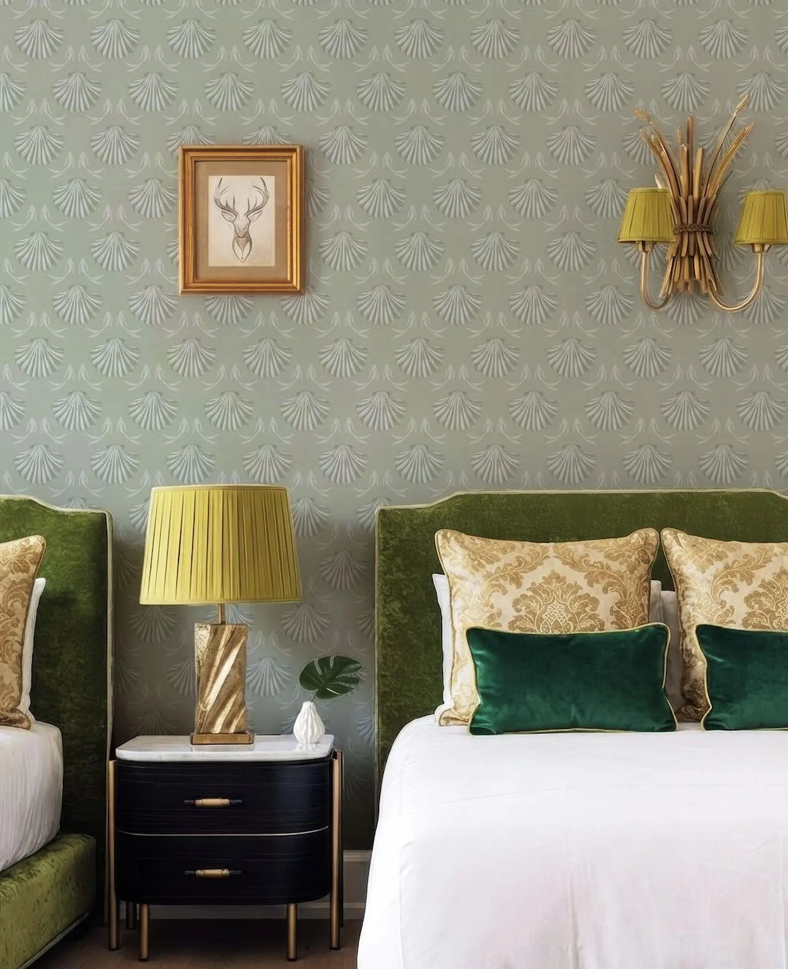 a well-decorated bedroom with a large bed, a nightstand, and a framed picture on the wall. The room has a green and gold color scheme, with a patterned wallpaper and a chandelier.