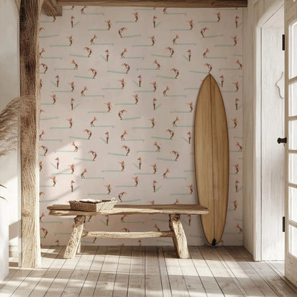 a wooden bench with a wicker basket on it, positioned in front of a wall with a repeating pattern of surfers riding waves. Next to the bench is a surfboard leaning against the wall.