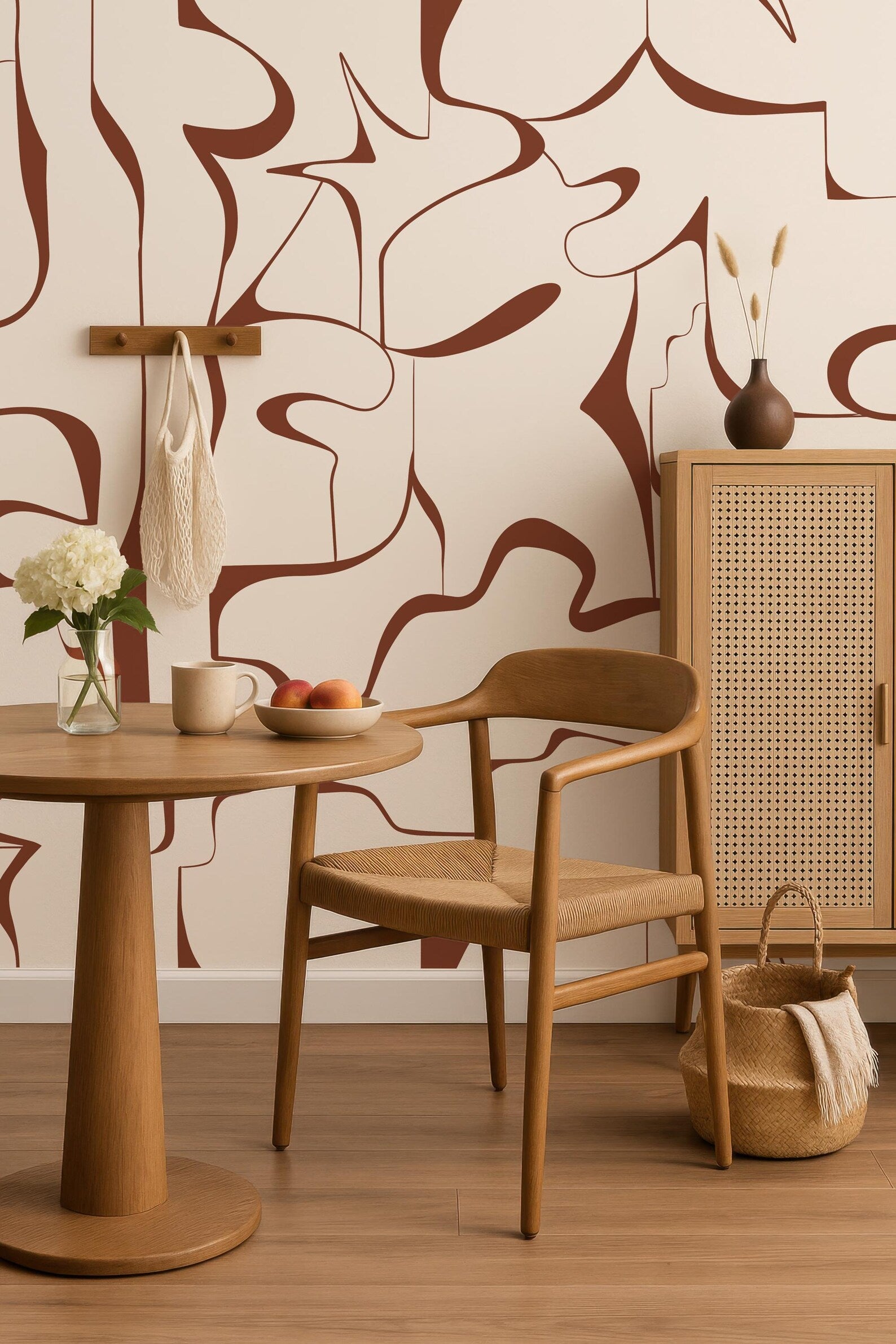 a cozy and stylish dining area with a wooden table, chair, and a woven basket. The table is set with a bowl of fruit, a vase of flowers, and a cup. The chair is positioned next to a woven cabinet, creating a harmonious and inviting atmosphere.