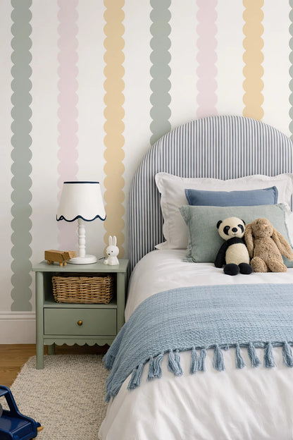 a cozy and colorful bedroom with a striped headboard, a blue blanket, and a nightstand with a lamp and a stuffed panda bear.