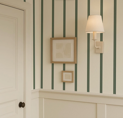 a corner of a room with a framed picture on the wall, a wall lamp, and a door.
