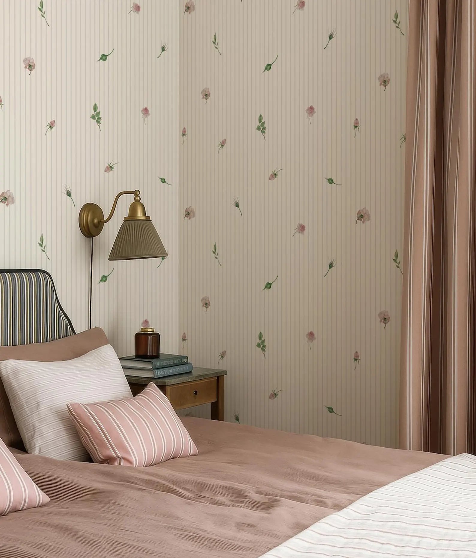 a cozy bedroom with a bed, a nightstand, and a lamp. The walls are covered in a floral wallpaper, and the bed is dressed in pink and white bedding.
