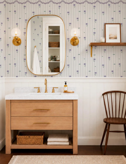 a well-organized bathroom with a wooden vanity, a mirror, and a shelf. The bathroom has a white and blue floral wallpaper, and the overall color scheme is neutral and calming.