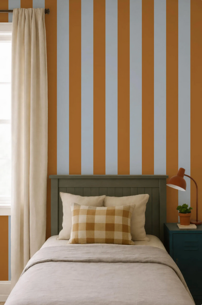 a bedroom with a bed, a nightstand, and a striped wall behind the bed. The bed has a checkered pillow and a lamp on the nightstand.