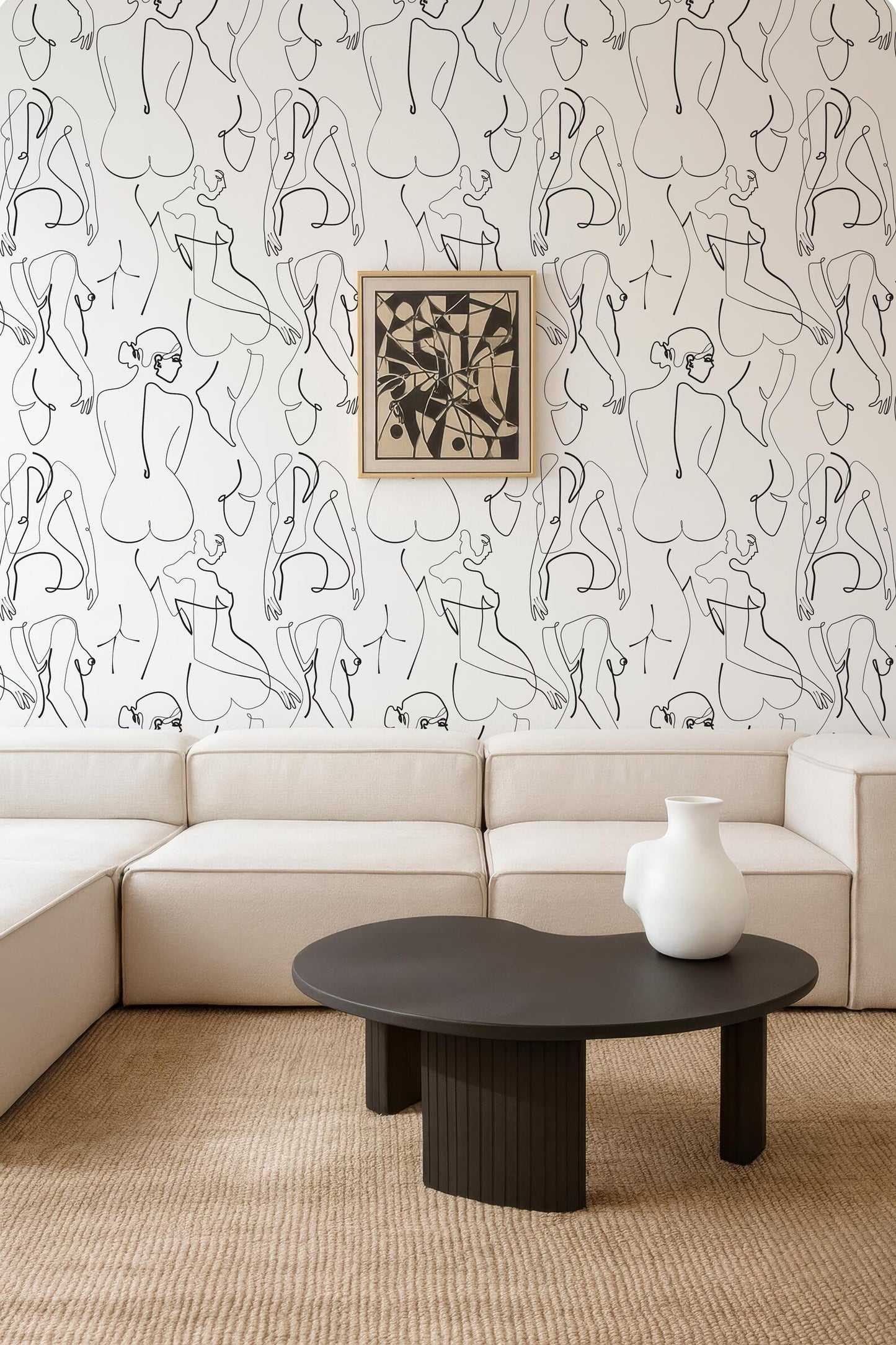a modern living room with a large abstract wall mural, a white sofa, a black coffee table, and a framed artwork on the wall.