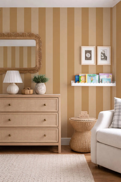a cozy and well-decorated living room with a striped wallpaper, a wooden dresser, a wicker side table, a white sofa, and a bookshelf filled with books.