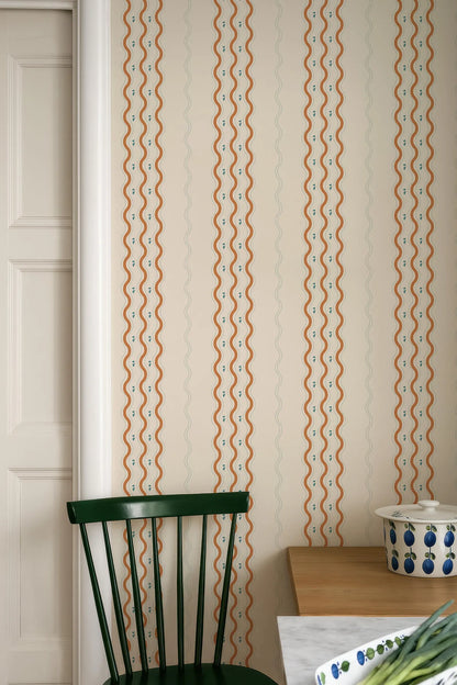 a kitchen interior with a green chair, a wooden table, and a patterned wall behind it.