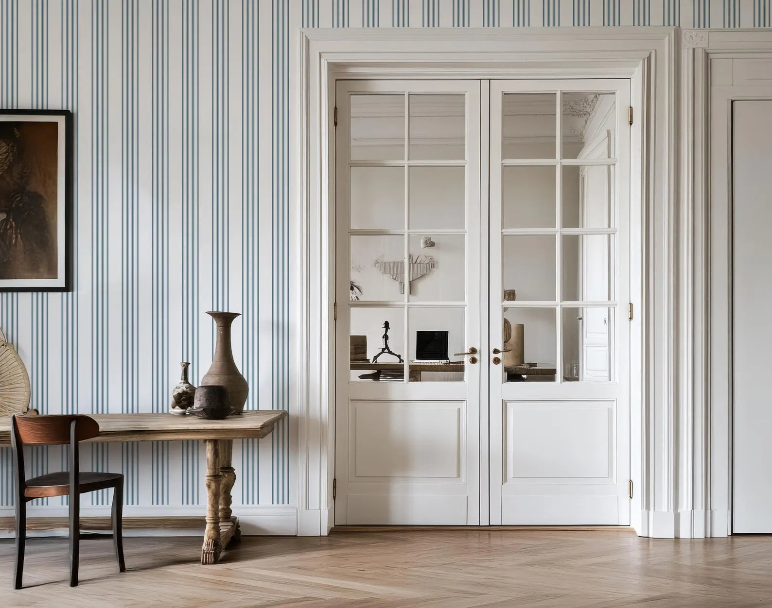a room with a wooden table, a vase, and a chair. The room has a striped wallpaper and a large window with white doors.