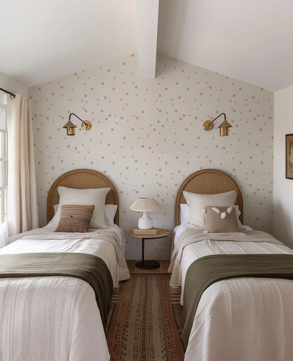 a cozy bedroom with two twin beds, each with a wooden headboard and white bedding. The walls are adorned with a star-patterned wallpaper, and the room features two wall sconces and a small side table with a lamp.