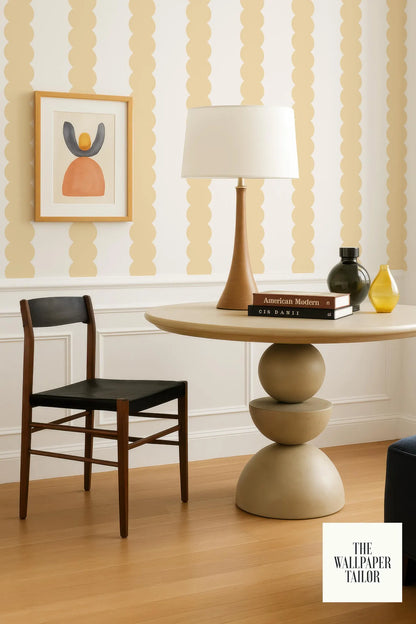 a modern and stylish living room with a wooden chair, a round table with a lamp, and a framed artwork on the wall.