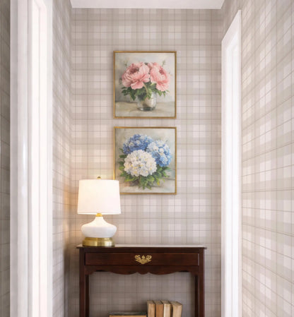 a cozy corner of a room with a wooden table, a lamp, and two framed paintings of flowers hanging on the wall above the table.