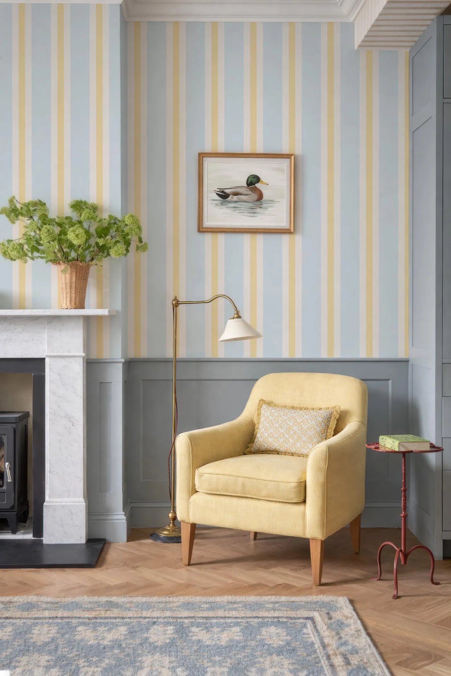 a cozy living room with a yellow armchair, a fireplace, and a framed picture of a duck on the wall.