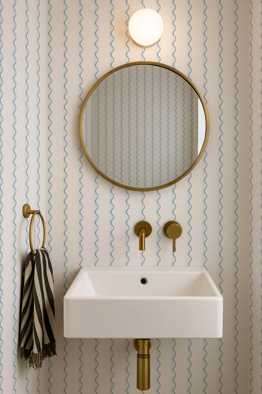 a bathroom with a white sink, a gold-framed mirror, and a striped towel.