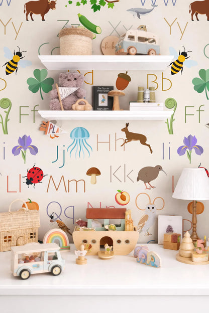 The image is a colorful and playful children's room, featuring a wall with a large alphabet wall mural and shelves filled with various toys and decorations.