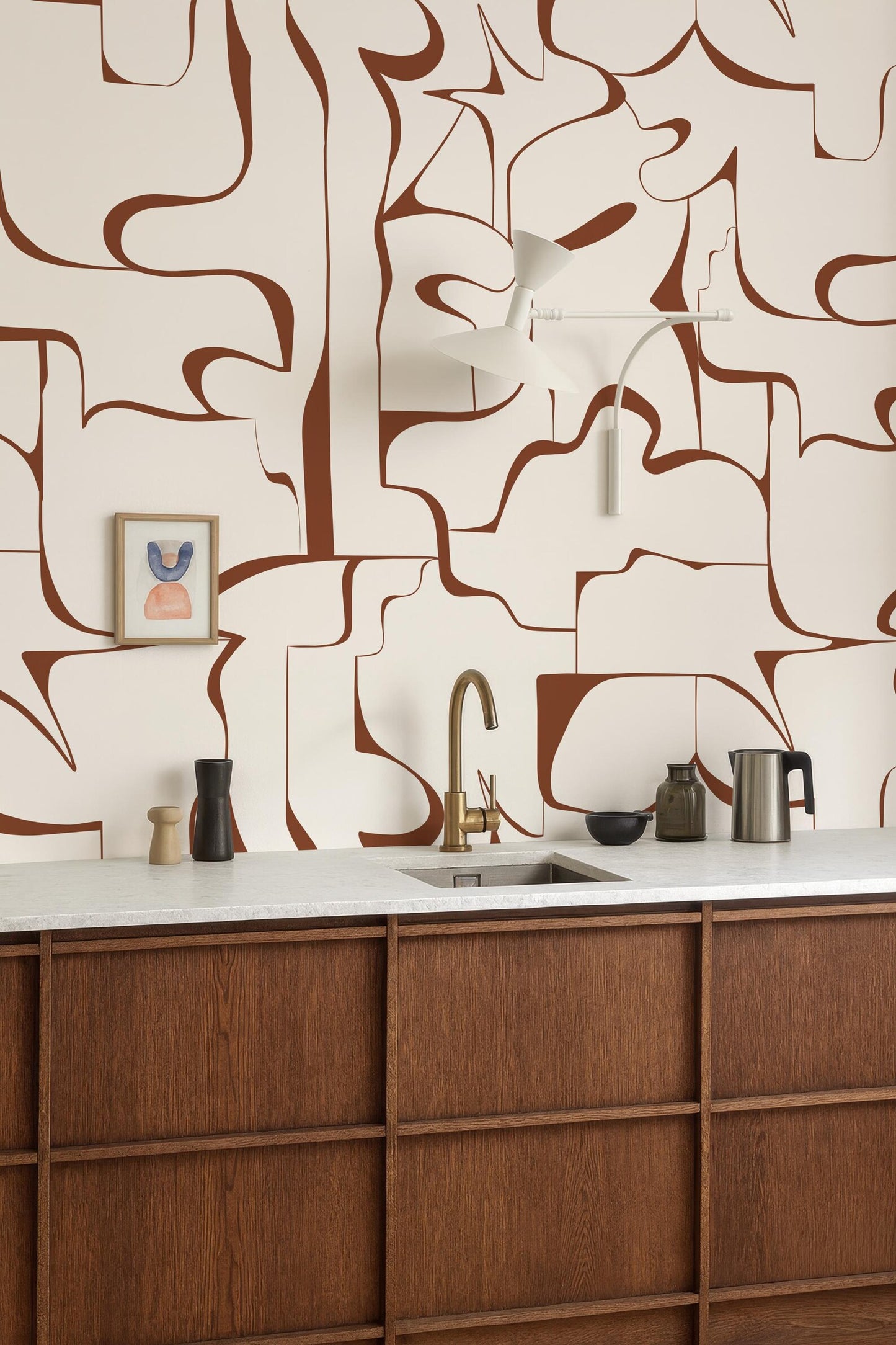 a modern kitchen with a wooden countertop and a sink. The walls are adorned with abstract brown and white patterns, creating a visually striking backdrop. On the countertop, there are various kitchen items such as a coffee maker, a bowl, and a vase.