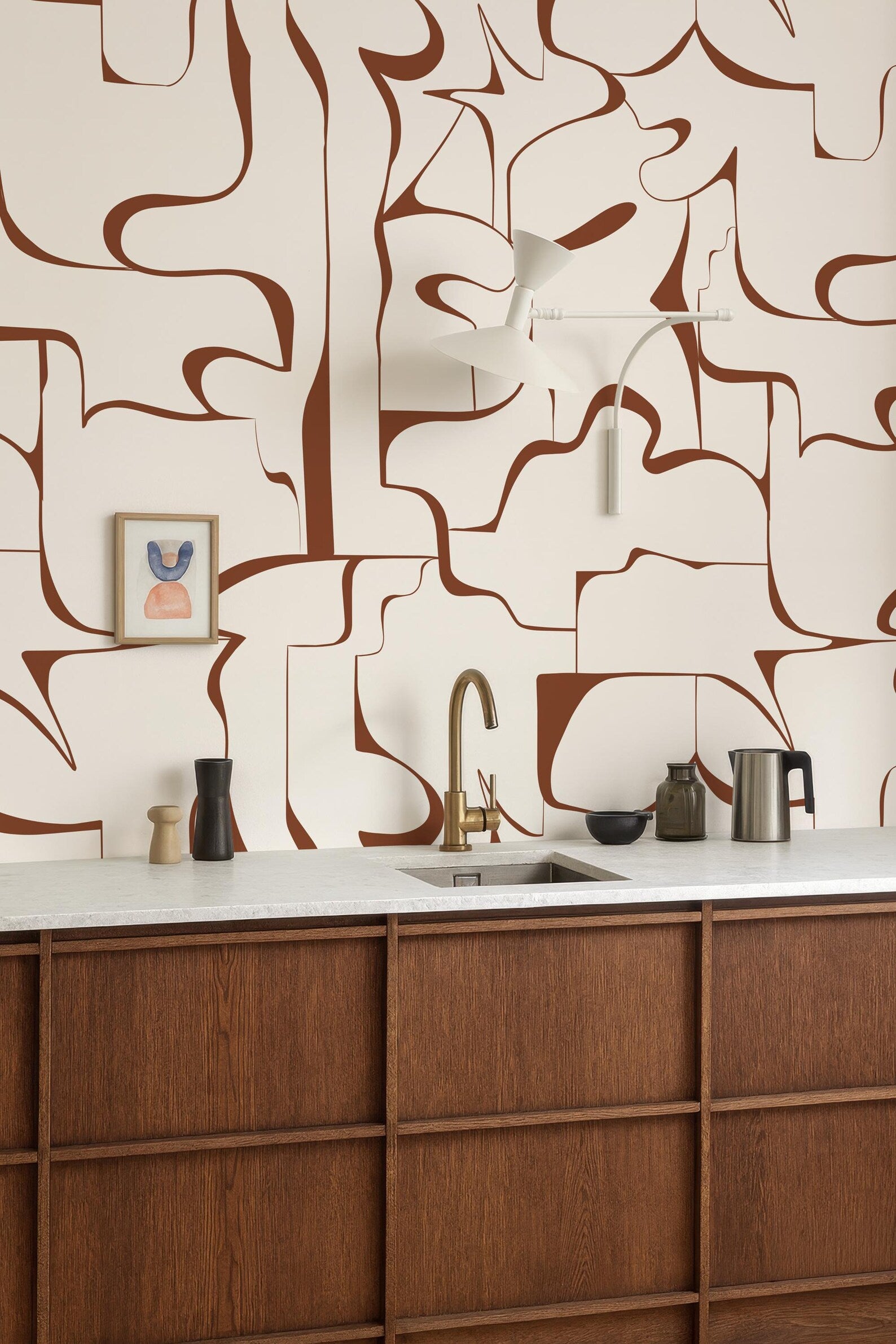 a modern kitchen with a wooden countertop and a sink. The walls are adorned with abstract brown and white patterns, creating a visually striking backdrop. On the countertop, there are various kitchen items such as a coffee maker, a bowl, and a vase.