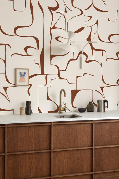 a modern kitchen with a wooden countertop and a sink. The walls are adorned with abstract brown and white patterns, creating a visually striking backdrop. On the countertop, there are various kitchen items such as a coffee maker, a bowl, and a vase.