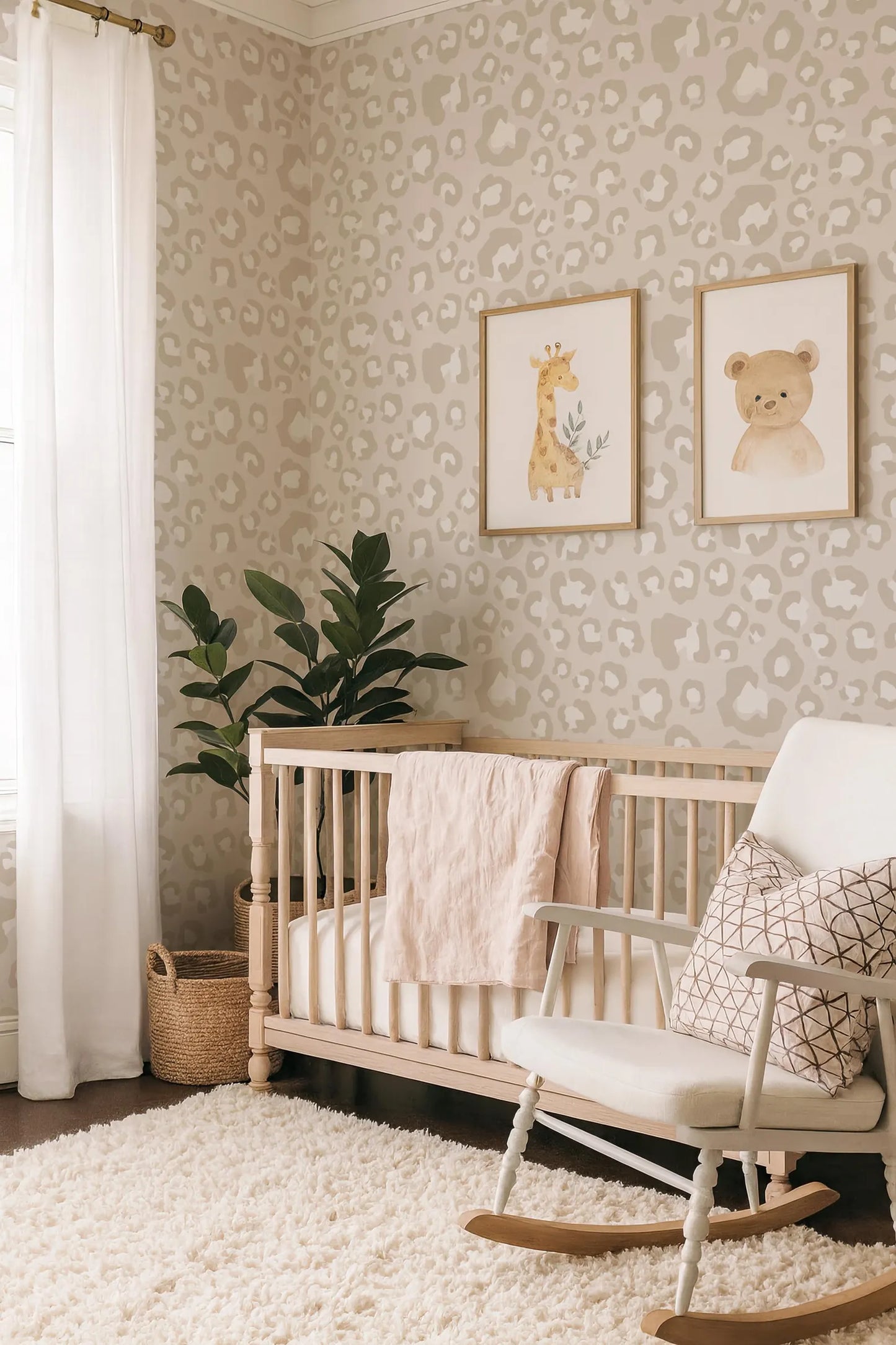 a cozy nursery with a wooden crib, a white rocking chair, and a potted plant. The walls are adorned with a leopard print wallpaper, and two framed animal prints are displayed above the crib.