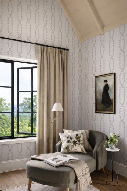 a cozy and inviting living room with a large window overlooking a scenic outdoor view. The room is adorned with a painting of a woman in a black dress, a lamp, and a comfortable armchair with a throw blanket. The overall decor and arrangement create a warm and welcoming atmosphere.