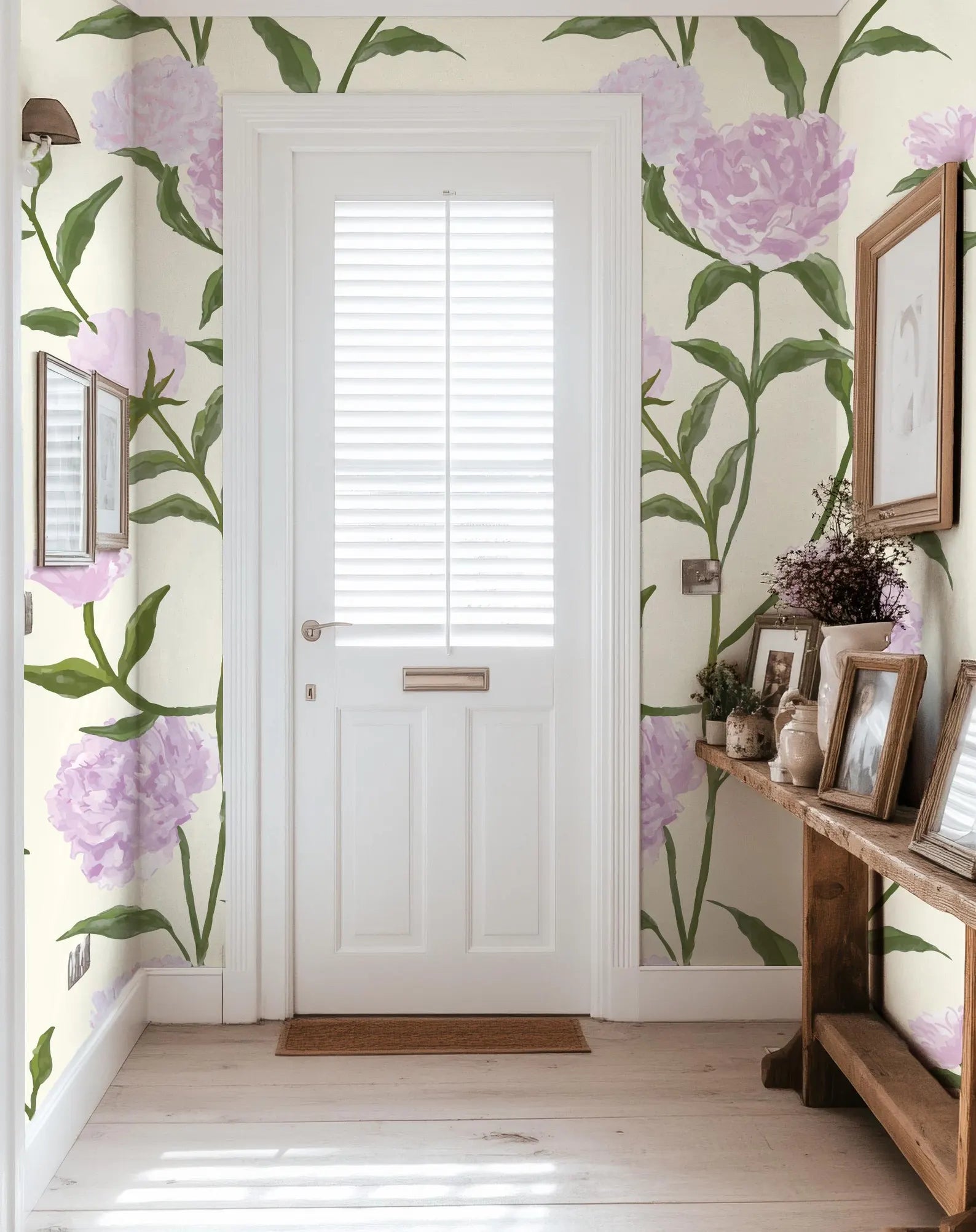 a hallway with a white door, a wooden table with framed pictures, and a wall with a floral wallpaper.