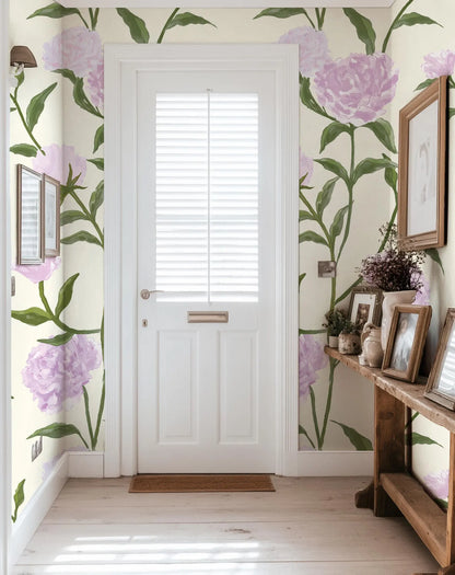 a hallway with a white door, a wooden table with framed pictures, and a wall with a floral wallpaper.