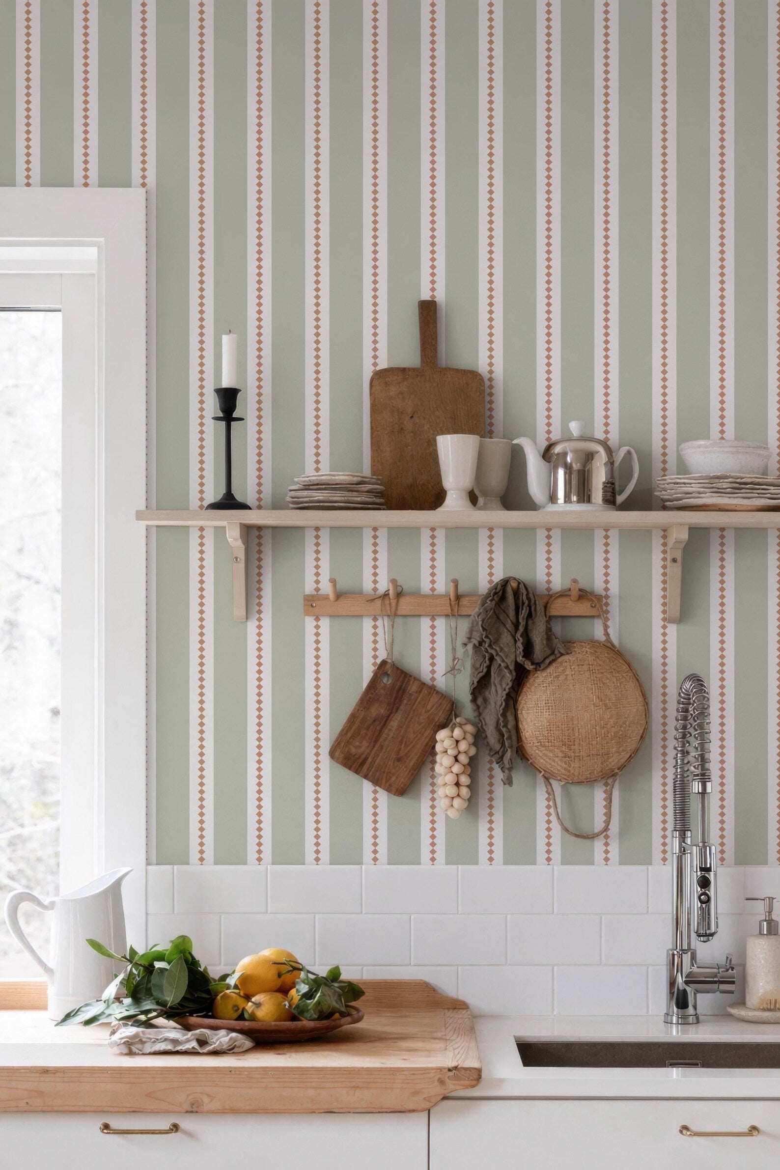 a kitchen with a wooden cutting board, a shelf with various kitchen items, and a sink with a fruit bowl on the counter.