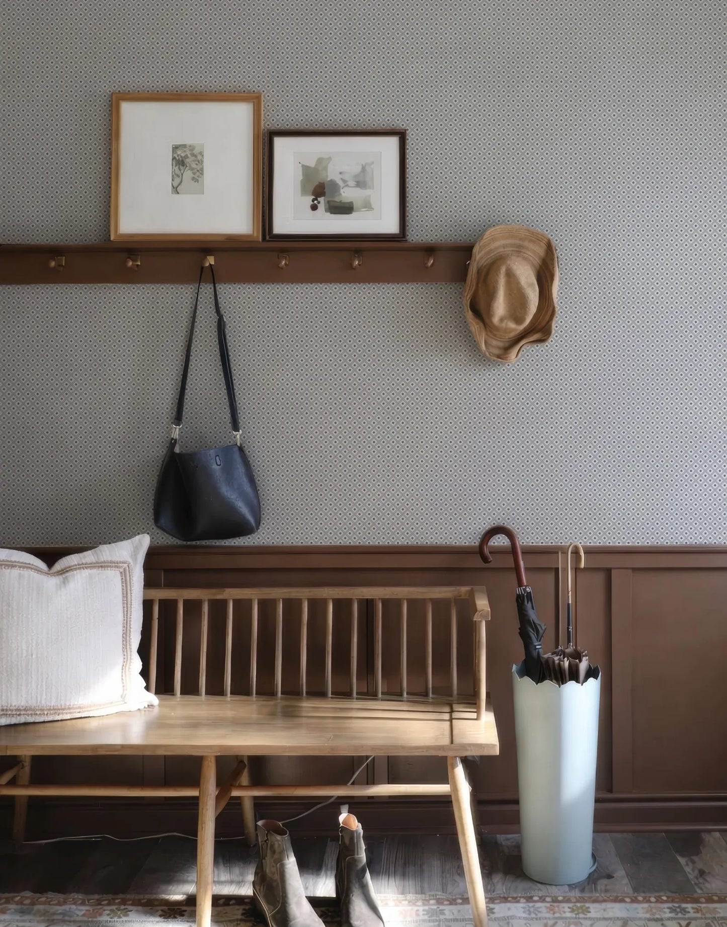 a cozy entryway with a wooden bench, a wall-mounted coat rack, and a hat rack. There are two framed pictures on the wall, a handbag hanging on the coat rack, and a pair of shoes placed on the floor.